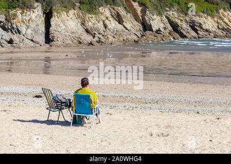 MAENPORTH, Falmouth, Cornwall, England - 18. September 2019: Person am Strand Stuhl bei Maenporth ein beliebtes Touristenziel in Cornwall, England. Stockfoto