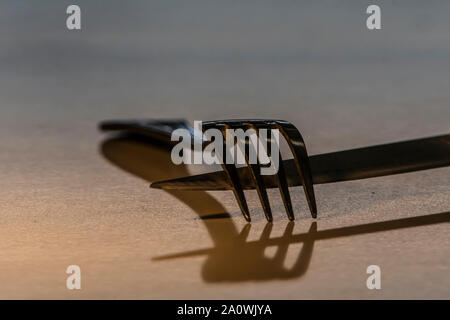 Künstlerische Ansicht der Messer und Gabel auf einem Teller. Konzeptionelle Bild über die Gefahr von Essen zu viel leckeres Essen. Stockfoto