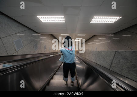 Bangkok/Thailand - 24. September 2018: Einsame Frau reist auf eine leere der u-bahn Rolltreppe in Bangkok, Thailand Stockfoto