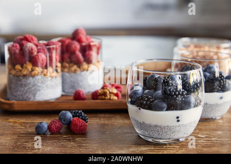 Selektiver Fokus Joghurt mit Chia Samen, Himbeeren, Heidelbeeren und Brombeeren in Gläsern in der Küche Stockfoto