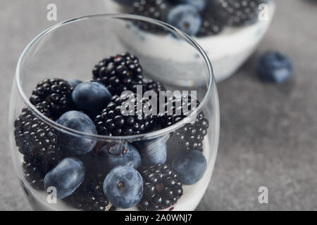 Selektiver Fokus der leckeren Joghurt mit Chia Samen, Heidelbeeren und Brombeeren in Gläsern Stockfoto