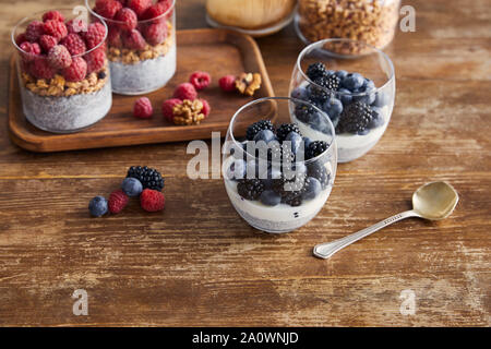 Frühstück mit Haferflocken, Joghurt mit Chia Samen und Beeren auf Holz- Fach auf Tisch Stockfoto