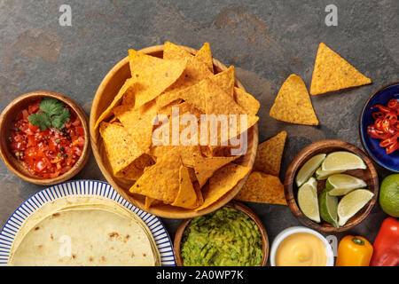 Blick von oben auf die Mexikanische nachos serviert mit Tortilla, Guacamole, Käse Soße und salsa auf steinernen Tisch Stockfoto