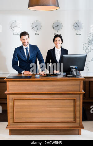 Freundliche Rezeptionisten in formale Abnutzung stehen an der Rezeption Stockfoto