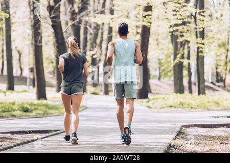 Rückansicht der jungen Sportler und Sportlerin, die auf Gehweg in Park Stockfoto