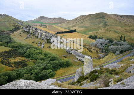 Eine Landschaft in Neuseeland mit dem Kalkstein Felsformation in der Nähe der Weka Pass, Hurunui District, South Island. Eine Reihe von Bäumen in der Mitte. Stockfoto