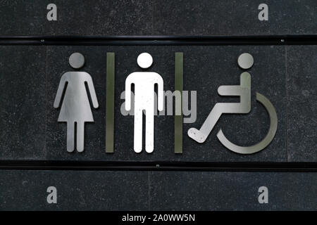 Wc Schild männlich weiblich behinderte Menschen glänzendes Metall gegen Schwarze dunklen Hintergrund. Öffentliche Toilette Schilder. WС Stockfoto