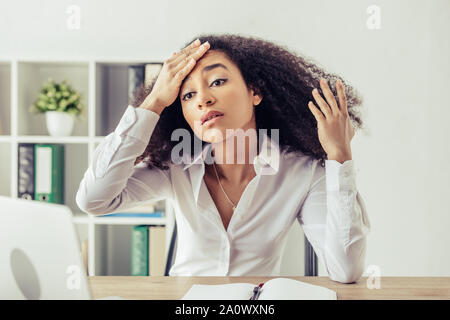 Ziemlich afrikanische amerikanische Geschäftsfrau, die Hand auf den Kopf und leiden unter Hitze im Büro Stockfoto