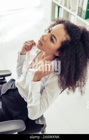 Hübsche junge afrikanische amerikanische Geschäftsfrau, die während des Leidens von der Sommerhitze im Büro Stockfoto