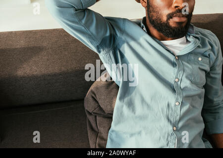 Teilweise mit Blick auf die afrikanische amerikanische Mann in verschwitzten Shirt sitzen auf dem Sofa und leidet unter Hitze Stockfoto