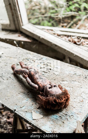 Selektiver Fokus von creepy verbrannt baby doll auf Holz beschädigt Schreibtisch Stockfoto