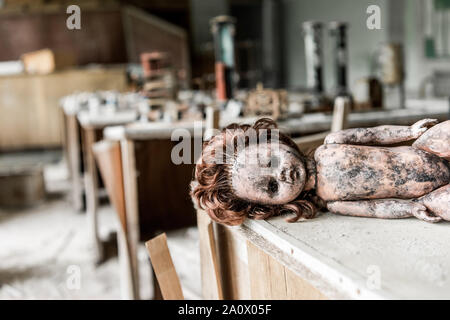 Selektiver Fokus von creepy baby doll auf hölzernen Schreibtisch im Klassenzimmer Stockfoto