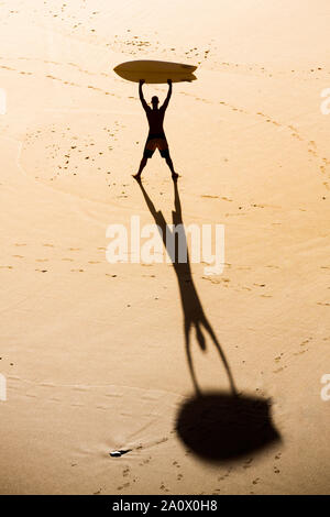 Blick von oben auf ein Surfer am Strand mit einem Surfbrett Stockfoto