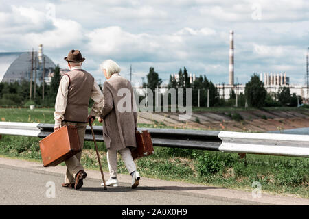 PRIPYAT, UKRAINE - 15. AUGUST 2019: Rückansicht der ältere Mann und Frau wandern mit Gepäck in der Nähe von Tschernobyl Stockfoto