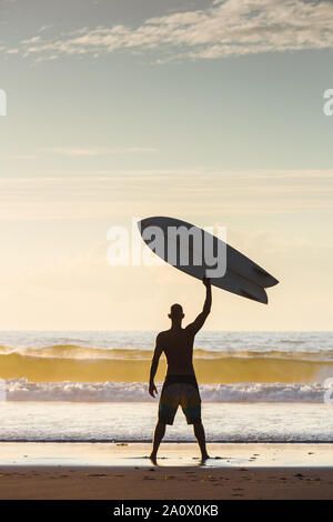 Surfer am Strand steigt surfboerd Stockfoto