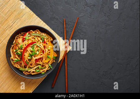 Vegetarische Schezwan Nudeln oder Gemüse Hakka Nudeln oder Chow Mein in schwarz Schüssel am dunklen Hintergrund. Indo-chinesischen Küche warmes Gericht mit udon Nudeln, Stockfoto