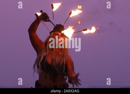 Feuer interpret Penella Biene führt, bevor die Menschen Teil im Norden Osten Skinny Dip an druridge Bay in Nothumberland, eine jährliche Veranstaltung, die Herbst-tagundnachtgleiche Marken und hebt Geld für die Mentale Gesundheit Nächstenliebe. Stockfoto