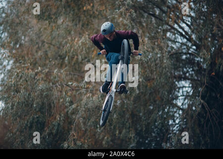 Professionelle junge Sportler Radfahrer mit BMX Bike machen akrobatische Tricks am Skatepark. Junger Mann bmx Biker, Stockfoto
