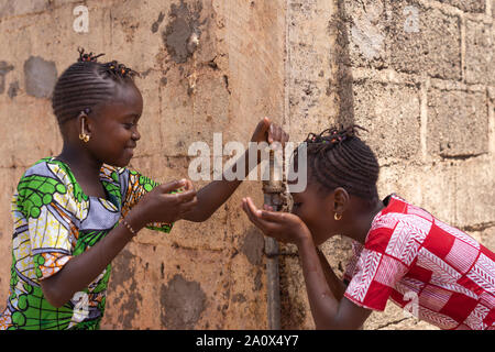 Zwei Mädchen glücklich Teilen Wasser aus in Bamako, Mali tippen Stockfoto
