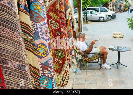 ANTALYA, Türkei - September 14, 2019: Verkäufer trading traditionellen türkischen Teppichen auf einer Straße in der Altstadt Kaleichi, Antalya, Türkei Stockfoto