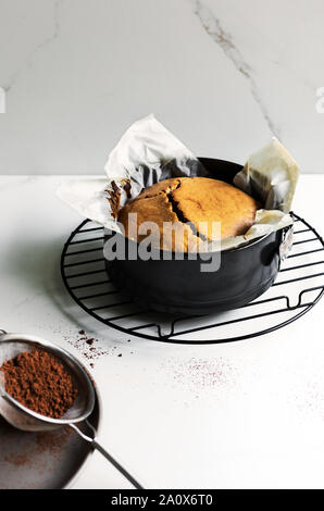 Frisch zubereiteten Kaffee Kuchen in eine Springform geben durch ein Sieb Stockfoto