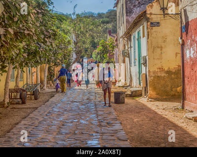 Goree, Senegal - Februar 2, 2019: Alltag und Straße mit Kopfsteinpflaster Straße zwischen Bunte Häuser auf der Insel Goree. Gorée. Dakar, Seneg Stockfoto