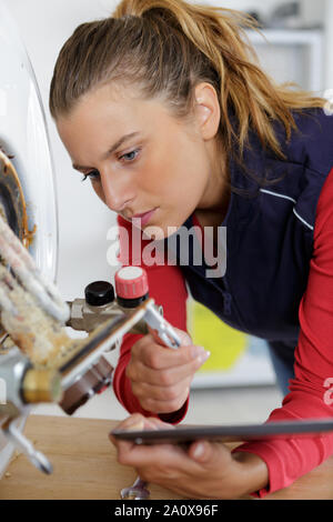 Weibliche Klempner Arbeiten an zentralen Heizkessel Stockfoto