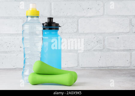 Wasserflaschen und Kurzhanteln auf hellen Hintergrund. Fitness, Sport und Gesundheit Konzept. Kopieren Sie Platz. Stockfoto