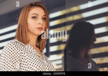 Porträt der jungen Frau an der Kamera schaut. Mädchen sitzen im Freien in der Nähe von Ihrem Büro oder Hochschule in formale Abnutzung mit langen Bob haircut Stockfoto