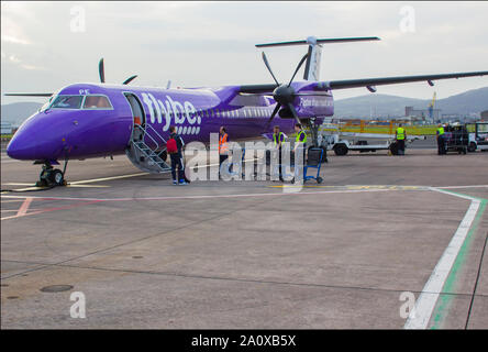 21. September 2019 eine FlyBe Dash 8 Verkehrsflugzeug mit Gepäck und Passagiere Handler auf dem Vorfeld des George Best City Airport in Belfast, Nordirland Stockfoto