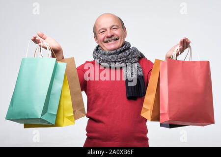 Senior Hispanic Mann mit farbigen Shopping bagsafter Shopping in der Mall. Stockfoto