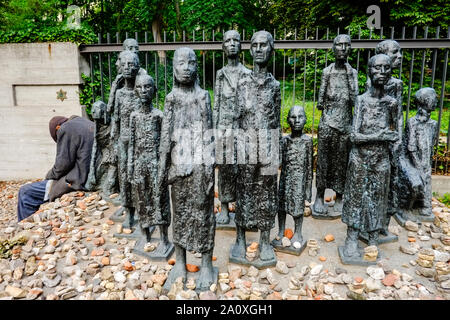 18 Juli 2019, Berlin: Ein alter Mann sitzt am Rand einer Gruppe von Figuren vom Bildhauer Willi Lambert Vor einem jüdischen Friedhof Große Hamburger Straße im Berliner Bezirk Mitte. Ist das erste Altersheim der Jüdischen Gemeinde von Berlin, im Jahre 1828 erbaut wurde, wurde hier entfernt. Es wurde von den Nationalsozialisten 1942 in ein Sammellager für jüdische Bürger umgewandelt, von denen 55.000 Juden in die nationalsozialistischen Konzentrationslager zusammengepfercht waren, bevor sie deportiert und ermordet. Foto: Stefan Jaitner/dpa Stockfoto