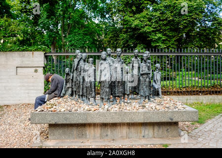 18 Juli 2019, Berlin: Ein alter Mann sitzt am Rand einer Gruppe von Figuren vom Bildhauer Willi Lambert Vor einem jüdischen Friedhof Große Hamburger Straße im Berliner Bezirk Mitte. Ist das erste Altersheim der Jüdischen Gemeinde von Berlin, im Jahre 1828 erbaut wurde, wurde hier entfernt. Es wurde von den Nationalsozialisten 1942 in ein Sammellager für jüdische Bürger umgewandelt, von denen 55.000 Juden in die nationalsozialistischen Konzentrationslager zusammengepfercht waren, bevor sie deportiert und ermordet. Foto: Stefan Jaitner/dpa Stockfoto