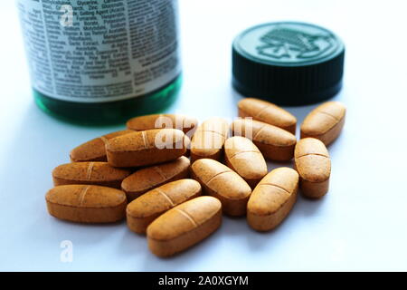 Multivitamin Tabletten und grünen Container, Flasche mit Etikett mit Nährwertangaben, Inhalt, und der empfohlenen täglichen Aufnahmemengen. Stockfoto