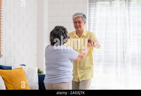 Asiatischer seniors Paar genießen Tanzen im Wohnzimmer zu Hause. Altern zu Hause Konzept Stockfoto