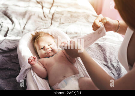 Mama Kleider ein neugeborenes Baby, bis ein jumpsuit Zuzuknöpfen. Home Comfort Stockfoto