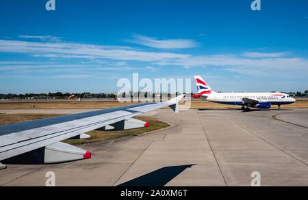 Blick aus dem Flugzeug Fenster von British Airways Flugzeug Rollen auf Start- und Landebahn am Flughafen Heathrow, London, England, Großbritannien Stockfoto