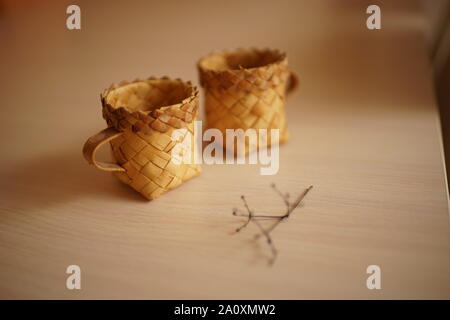 Zwei wicker Tassen und einem trockenen Blume auf dem Tisch Stockfoto