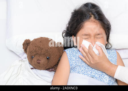 Mutter, der die Nase von ihrer Tochter, kranken Mädchen liegt auf dem Bett, Health Care Konzept Stockfoto