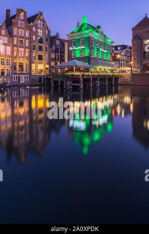 Ein Abend in Amsterdam, mit dem Blick auf die Heuschrecke und die Oude Kerk (Alte Kirche) im Hintergrund, das älteste Gebäude in Amsterdam. Stockfoto
