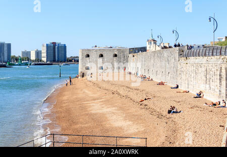 Menschen sonnen sich am Strand von Portsmouth Harbour, der runde Turm im Hintergrund, Portsmouth, Großbritannien Stockfoto