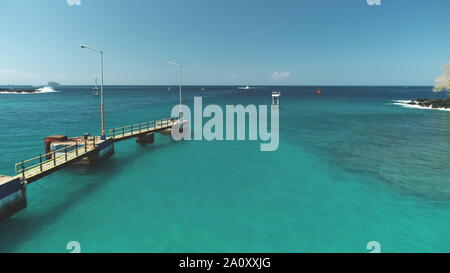 Antenne Drone Flug über Türkis Kristall Meer Wasser, Hafen, Port, Pier in hellen, sonnigen Tag. Reisen Transport entspannen Tourismus Konzept. Tropisches Paradies Insel Bali, Indonesien. Filmische Stockfoto