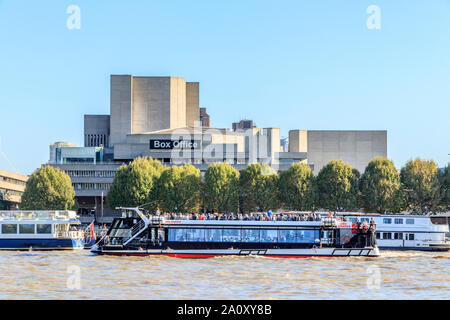 Eine Stadt Kreuzfahrten Boot vorbei vor der nationalen Theater, über die Themse von der Victoria Embankment, London, UK Stockfoto