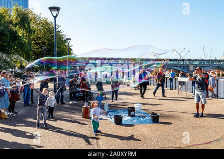 Kinder genießen große Blasen auf der South Bank der Themse in Bankside, London, UK Stockfoto