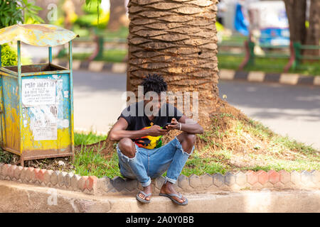 BAHIR DAR, Äthiopien, APRIL 21 th. 2019, junge Mann verwenden Sie smart, Handy auf der Straße von Bahir Dar während der Osterferien. April 21 th. 2019, Bahir Dar Stockfoto