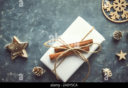 Weihnachtsgeschenk mit Zimtstangen auf grauem Hintergrund eingerichtet. Kopieren Sie Platz. Flach Stockfoto