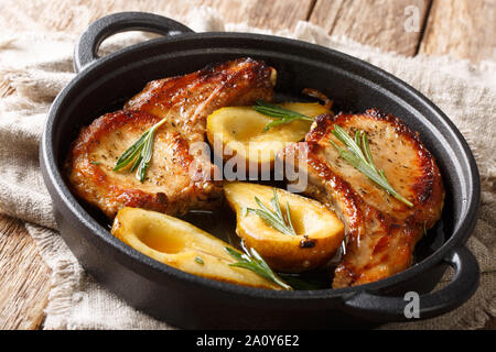 Landhausstil gebackene Schweinerippchen mit Birnen und Rosmarin in Honig - Knoblauch Sauce serviert in einer Pfanne close-up auf dem Tisch. Horizontale Stockfoto