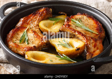 Gebratene Schweinekoteletts mit Rippen mit Birnen und Rosmarin in Honig Sauce serviert in einer Pfanne close-up auf dem Tisch. Horizontale Stockfoto
