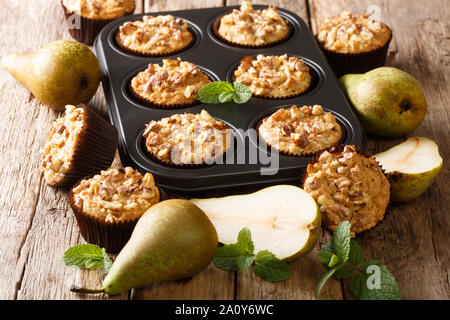 Nur aus dem Backofen Birnen Muffins mit Nüssen, Zimt und Muskatnuss in einer Auflaufform close-up auf dem Tisch. Horizontale Stockfoto