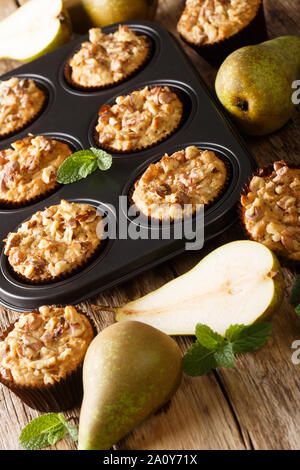 Frisch gebackene Birnen Muffins mit Zimt und Walnüsse in einer Auflaufform close-up auf dem Tisch. Vertikale Stockfoto